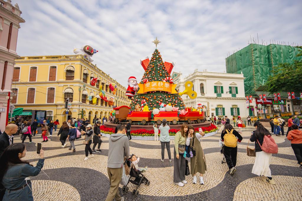 12月12日,游客在澳門議事亭前地的圣誕樹前拍照。新華社記者 朱煒 攝